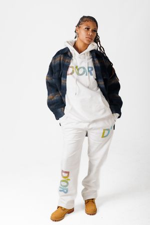 A person wearing a white hoodie, denim jacket and tan boots poses against a white background in three different stances.