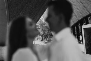 A couple shares a tender moment during a wedding ceremony while guests watch in the background.