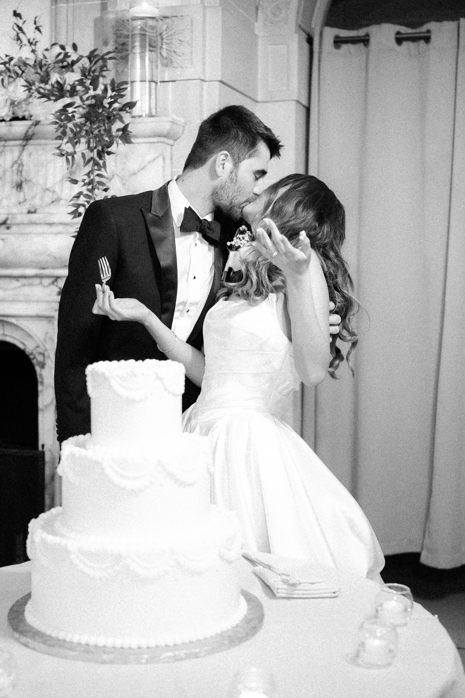 A series of black and white wedding photos showing a couple cutting their traditional white tiered cake at their reception.