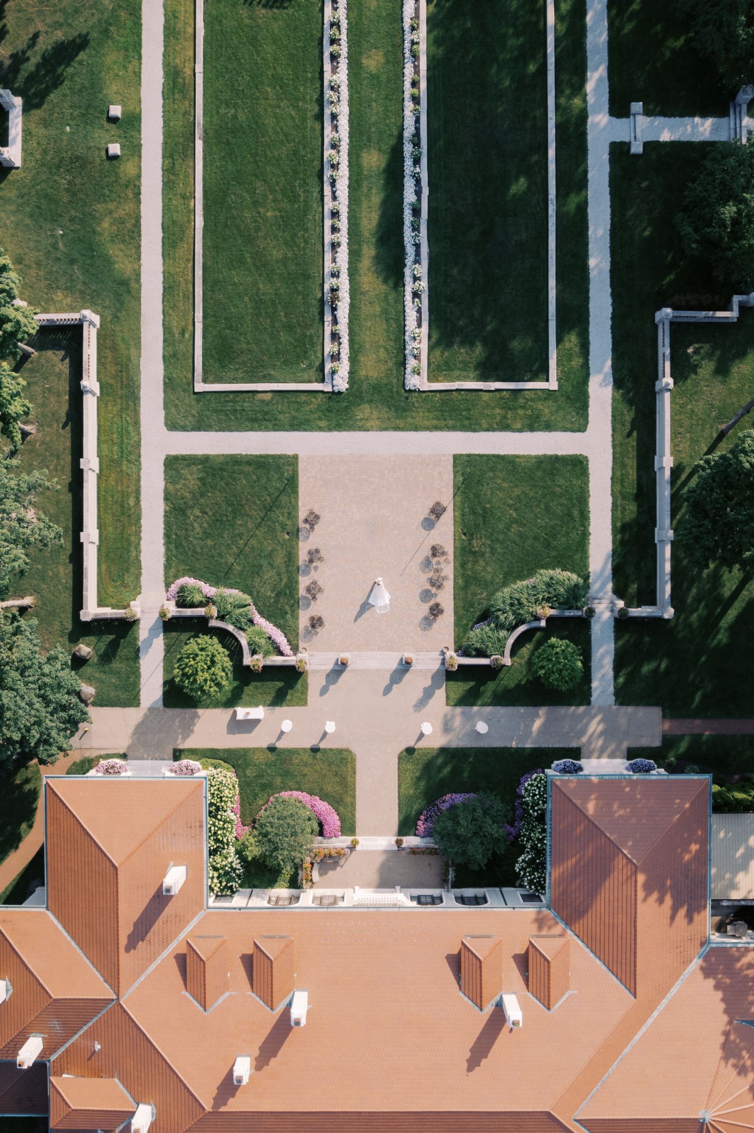 Aerial view of a terracotta-roofed building with manicured green lawns and geometric pathways.