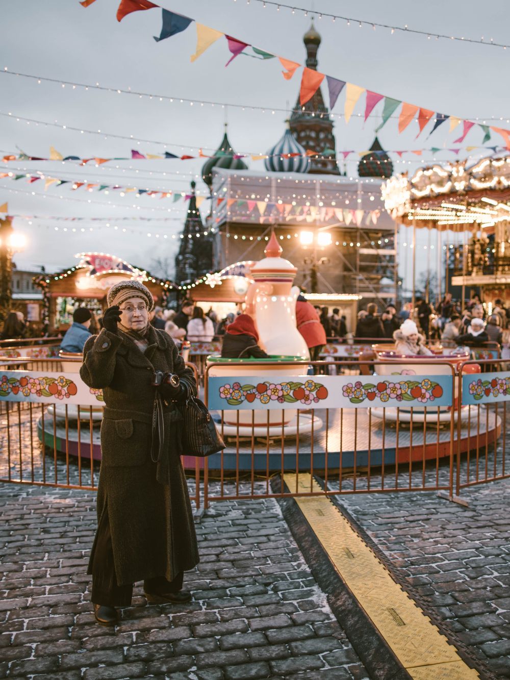 Colorful bunting flags wave above Red Square in Moscow during winter festivities with Saint Basil's Cathedral in view.