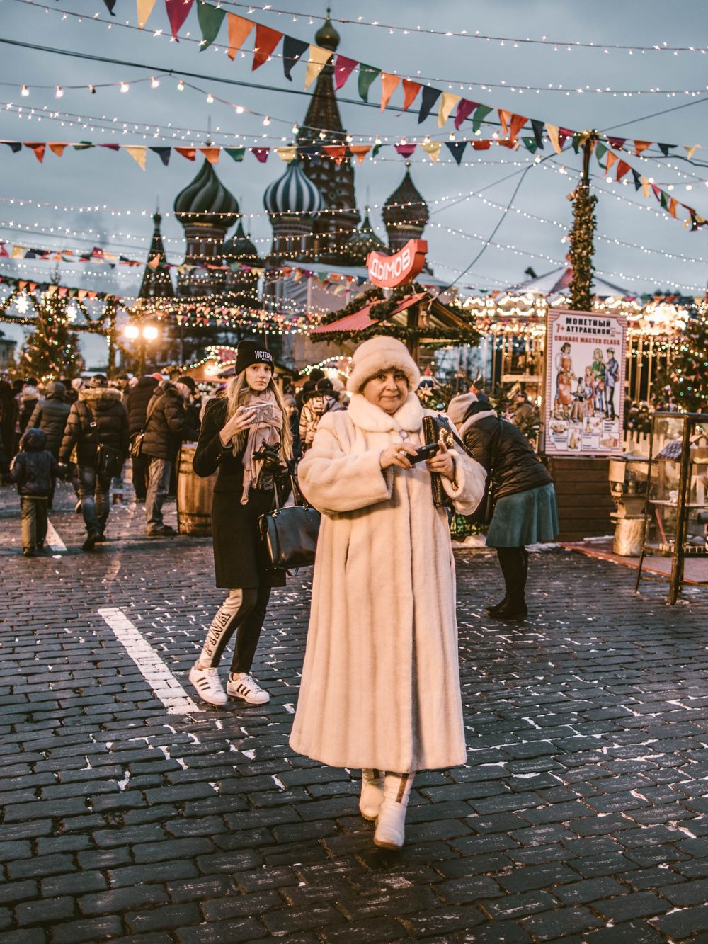 Festive scene at Red Square in Moscow with colorful bunting and string lights decorating the cobblestone plaza.