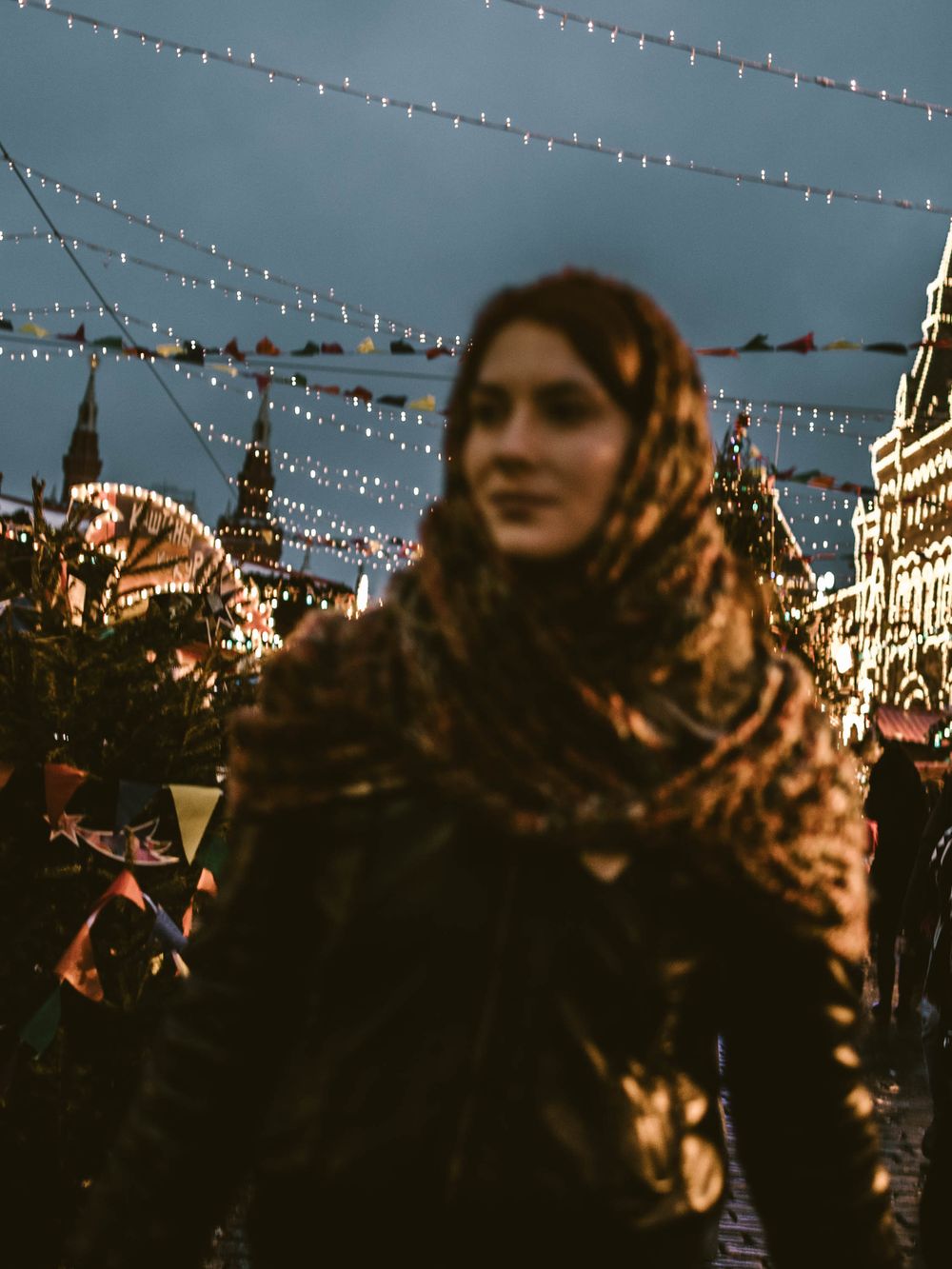 String lights illuminate an evening city street with historic buildings and people enjoying the nighttime atmosphere.