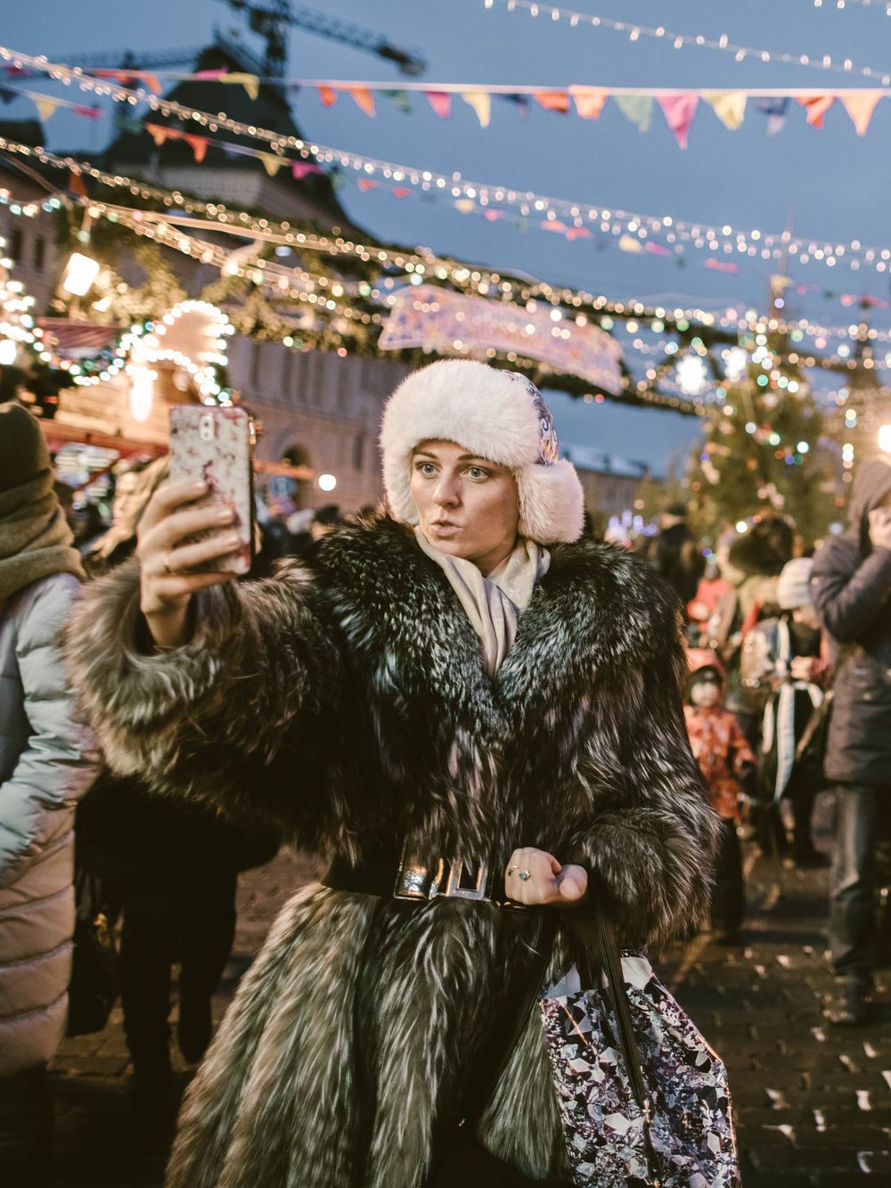 People enjoying a festive outdoor night market with string lights and decorative bunting creating a magical atmosphere.