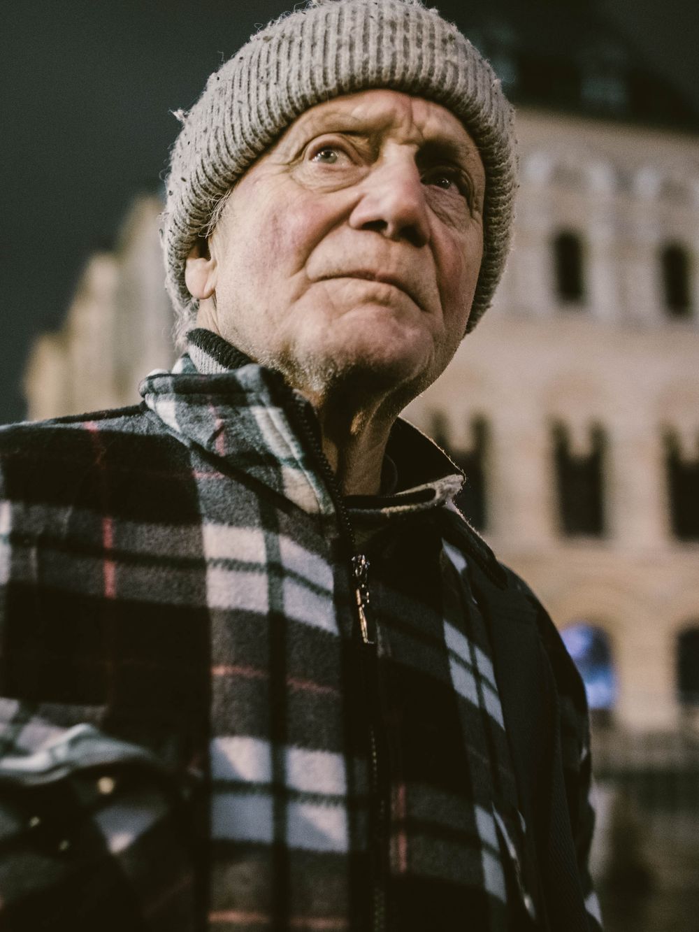 Close-up portraits of an elderly person wearing a knit hat and plaid scarf in winter.