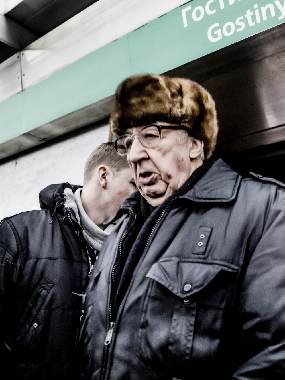 A sequence of five photos showing two people in dark winter coats having a close conversation in front of a mint green wall.