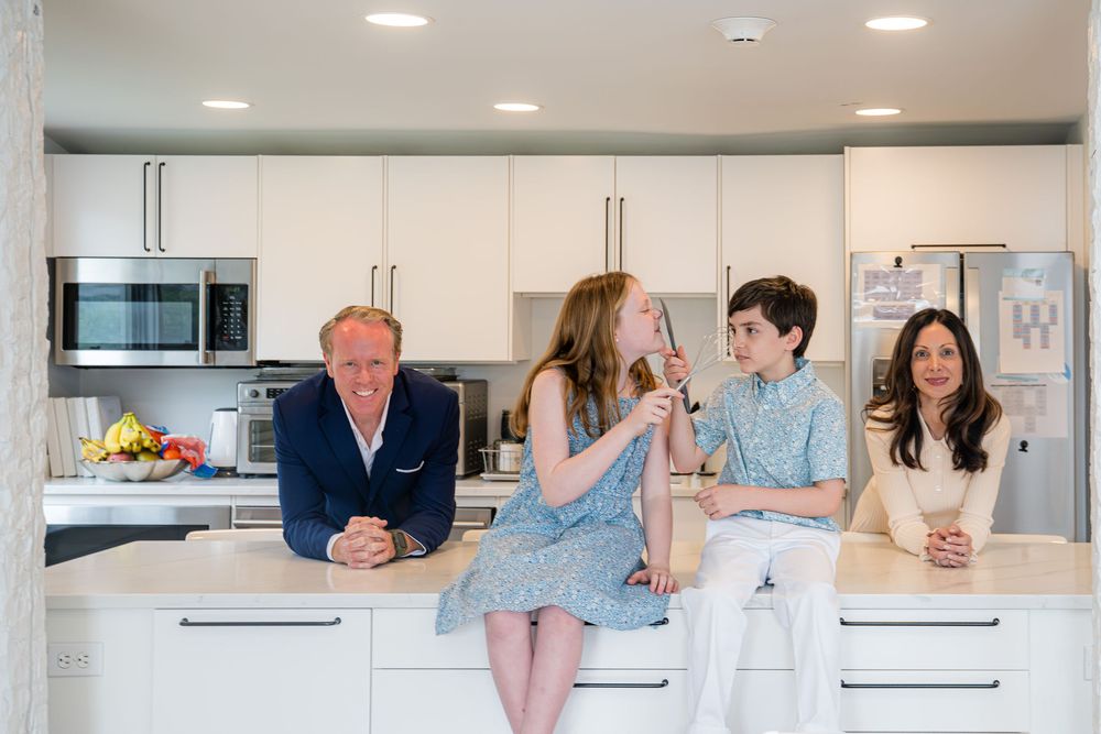 Westport family gather around a modern white kitchen island with the kids making silly gestures while everyone is smiling.