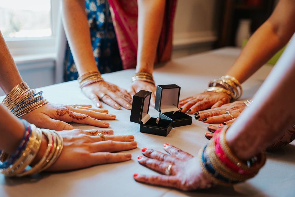 Close-up view of hands adorned with colorful bangles and henna designs during a traditional Indian wedding ceremony.