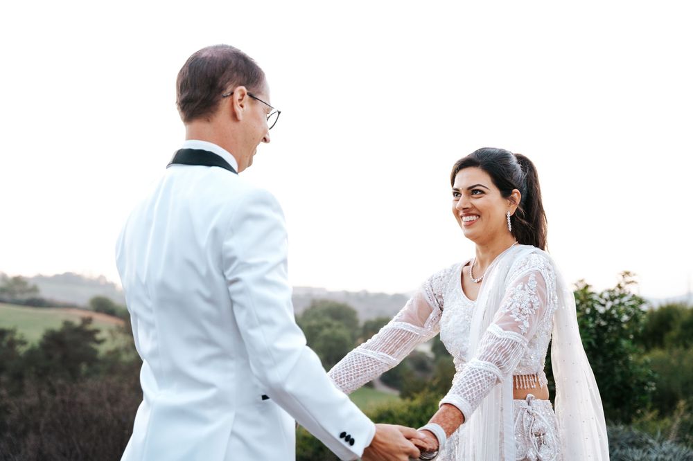 A couple in white wedding attire shares a joyful moment outdoors during their wedding photoshoot.