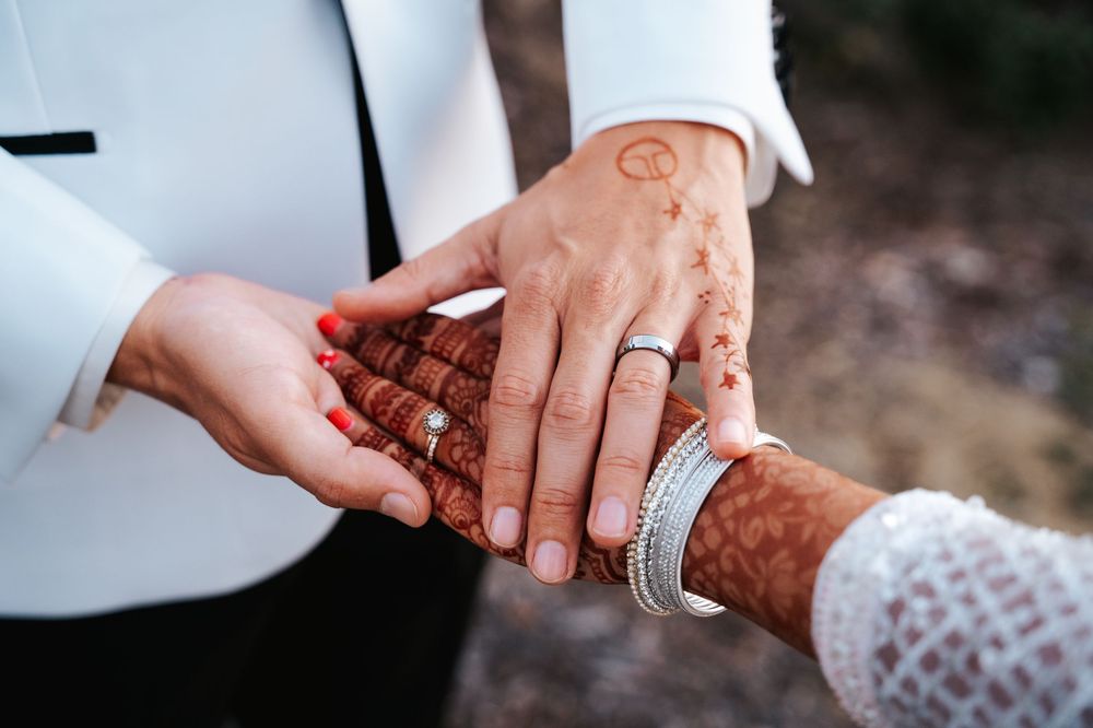Close-up view of hands exchanging wedding rings during an outdoor ceremony.