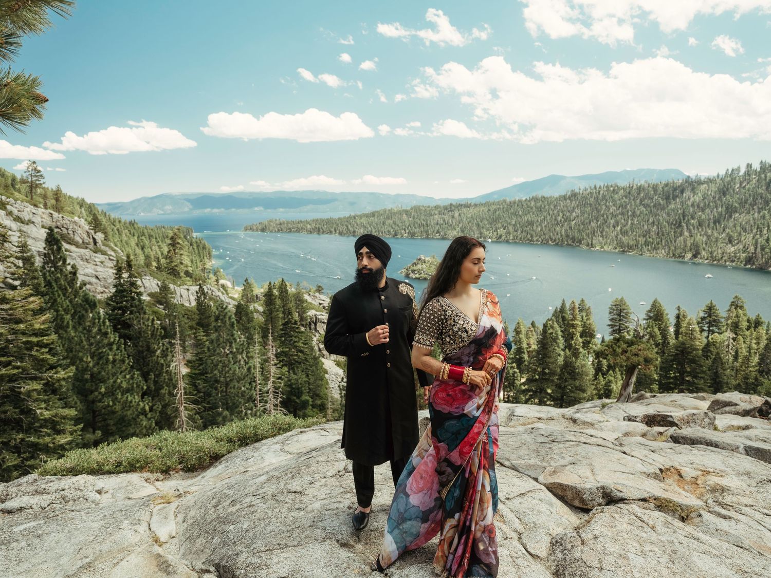 Scenic mountain landscape overlooking a lake with pine trees and rocky cliffs on a sunny day.