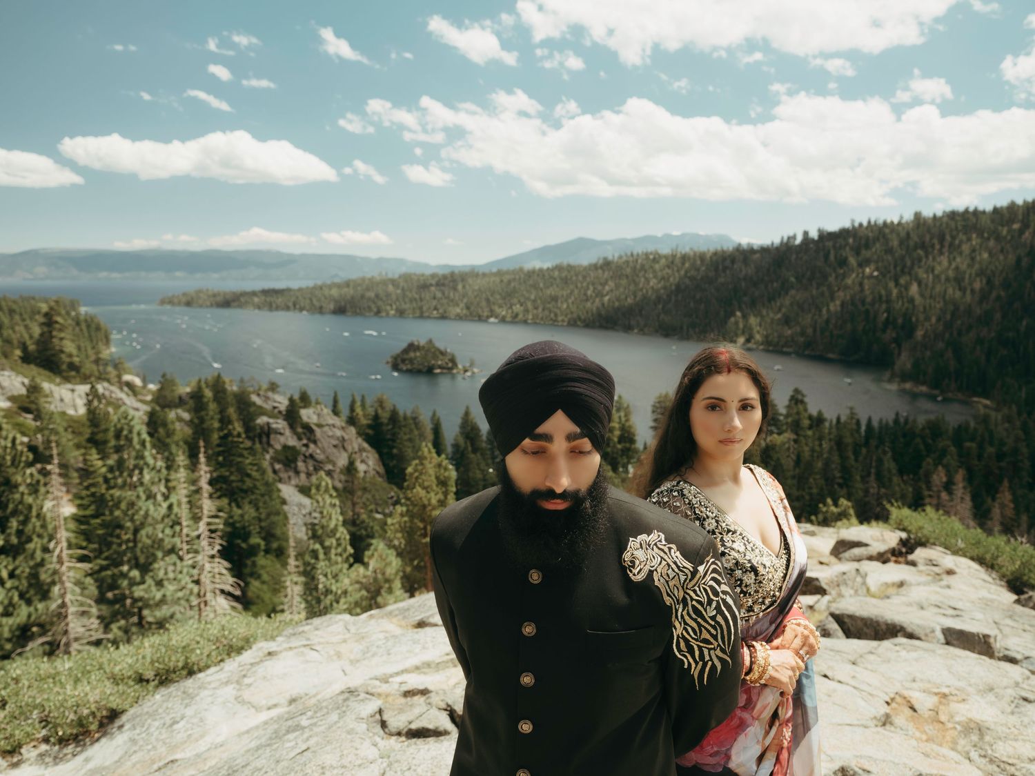 Couple enjoys scenic mountain views from rocky overlook at Lake Tahoe surrounded by evergreen forests.