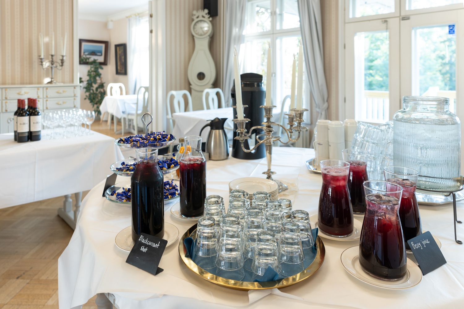 Elegant white dining room with crystal chandelier, marble table, and large windows letting in natural light.