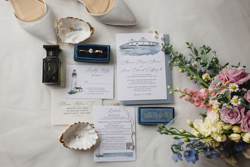 Wedding details including invitations, rings, shoes, and floral arrangements laid out on a light surface.