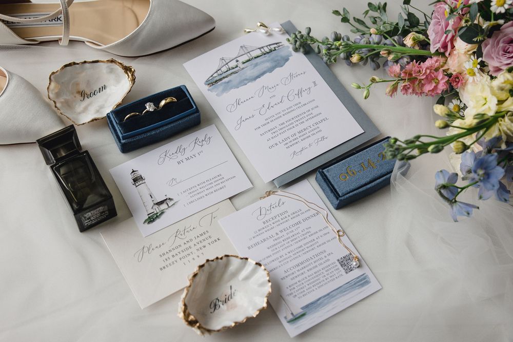 Wedding details including rings, invitations, and delicate floral arrangements on a light surface.