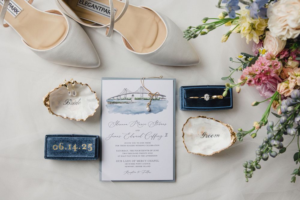 Wedding details including elegant shoes, floral arrangements, and invitation cards laid out on a light surface.