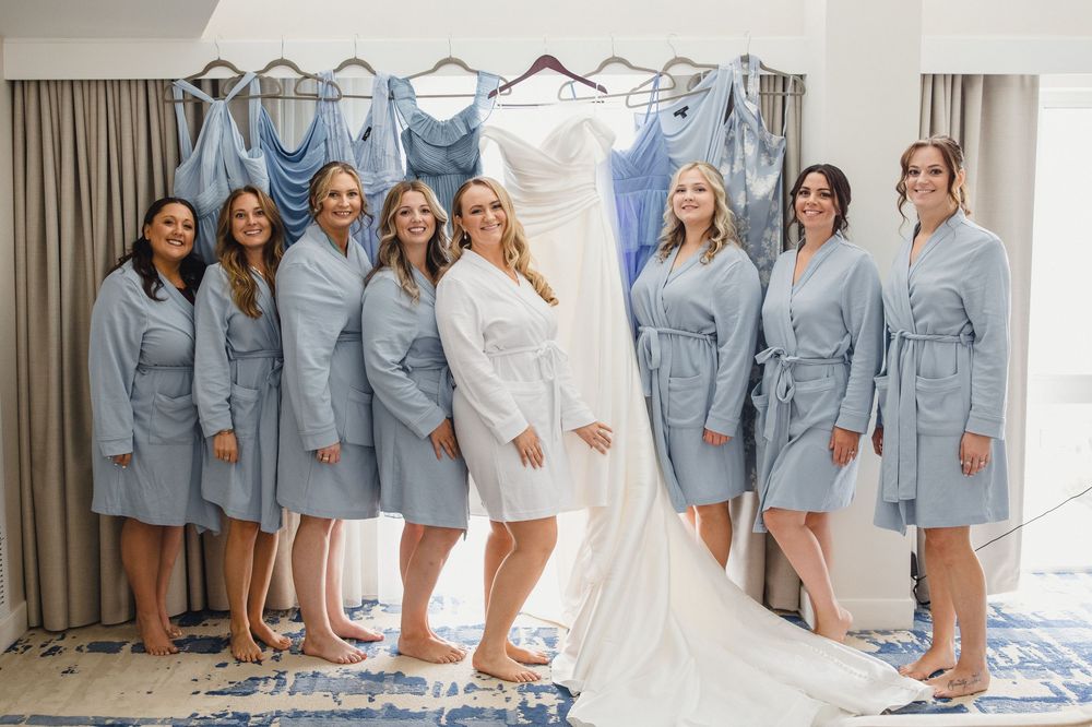 Bridesmaids in light blue robes gather together during wedding preparations.