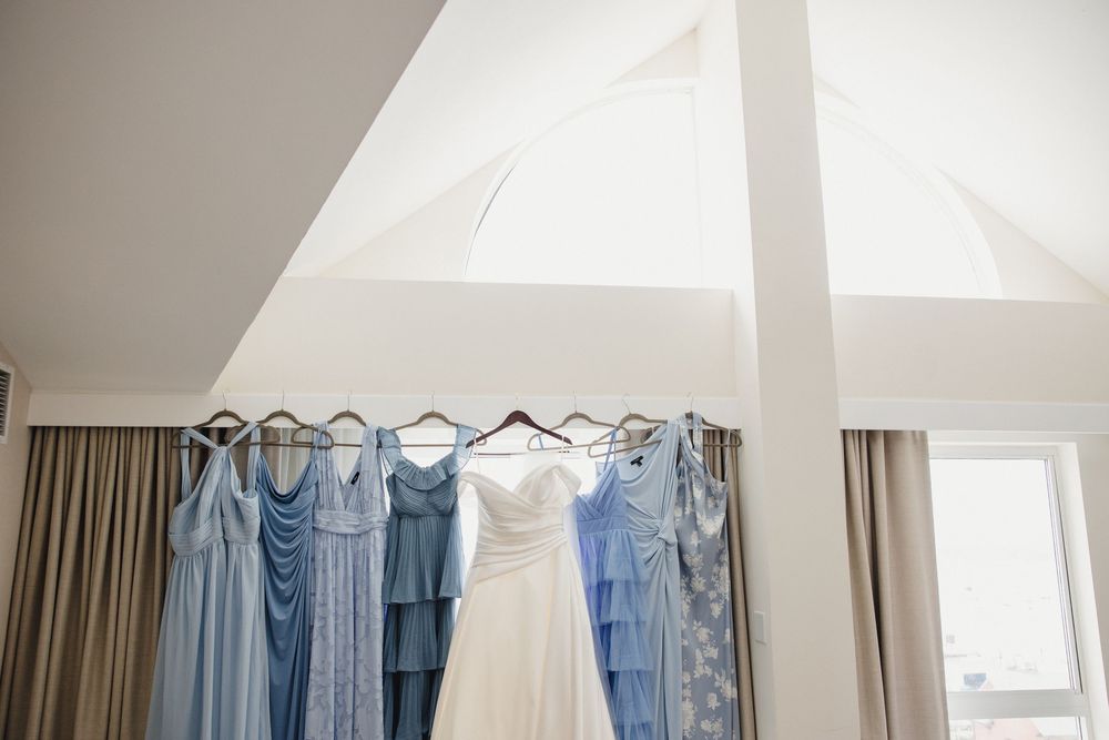 Row of light blue bridesmaid dresses hanging on display in a bright room.