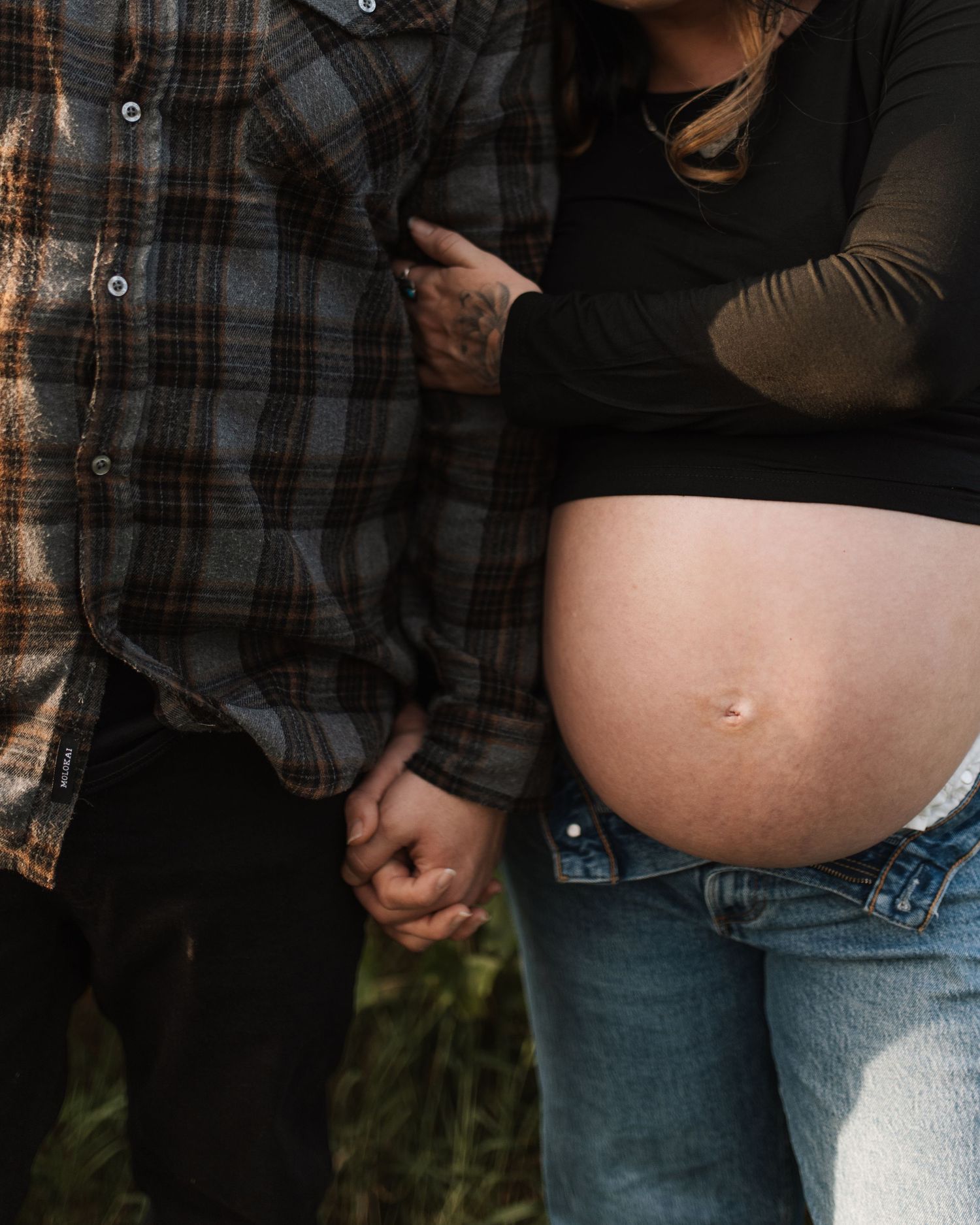 A series of maternity photos showing a pregnant belly against a dark background.