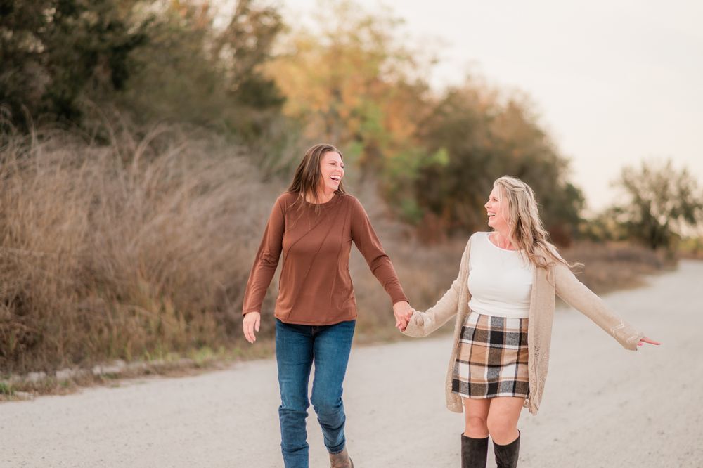 Two people walking hand in hand on a dirt path during golden hour at sunset.