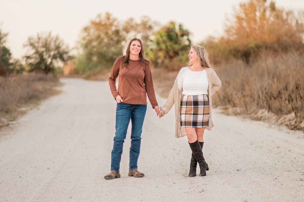 A couple walking together on a dirt path during golden hour in autumn.