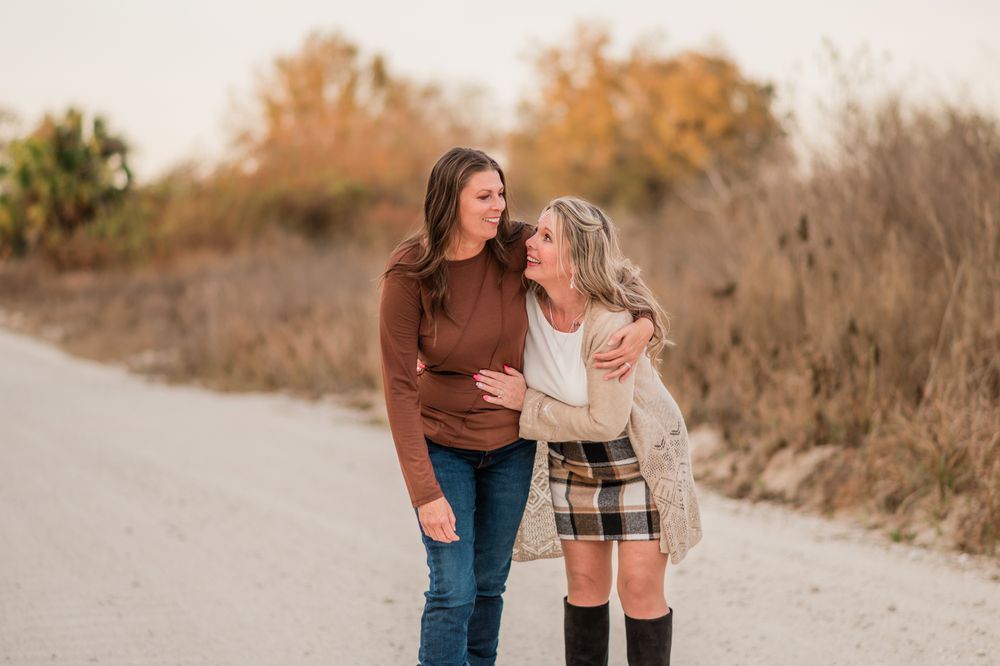A couple walks together on a dirt path during golden hour, sharing intimate moments in nature.