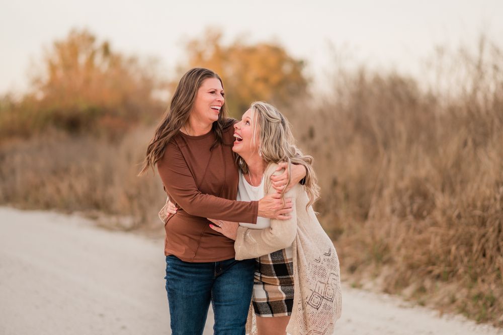 A couple embraces on a dirt path during golden hour with autumn foliage in the background.