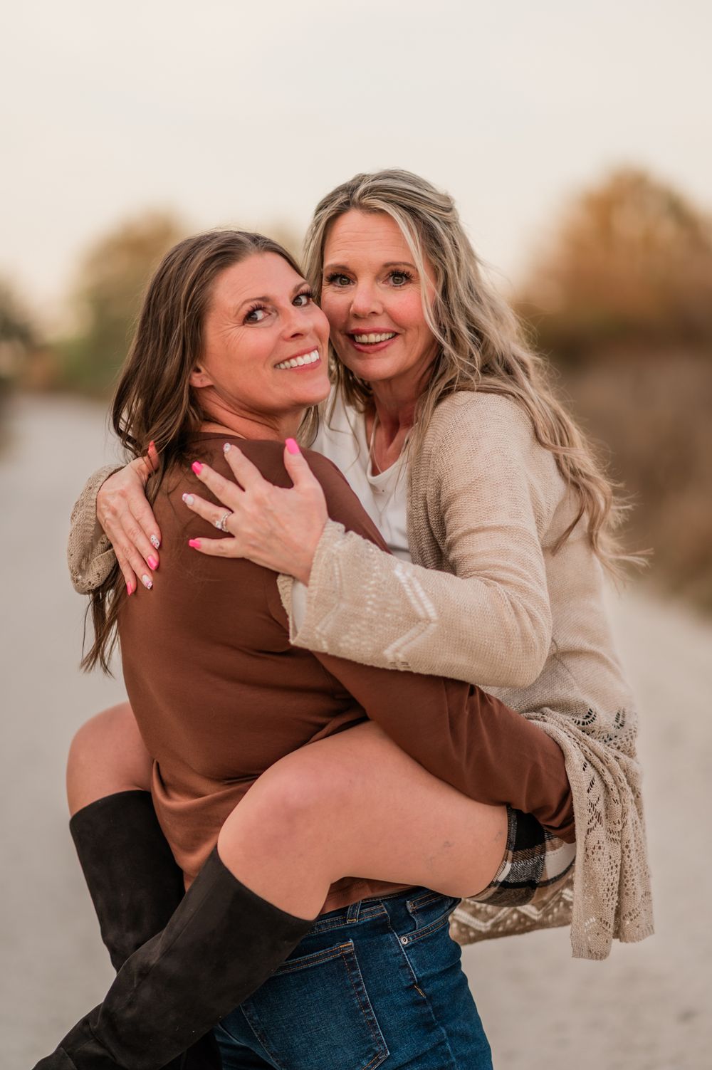 Two people sharing playful and affectionate moments on a dirt path at sunset.