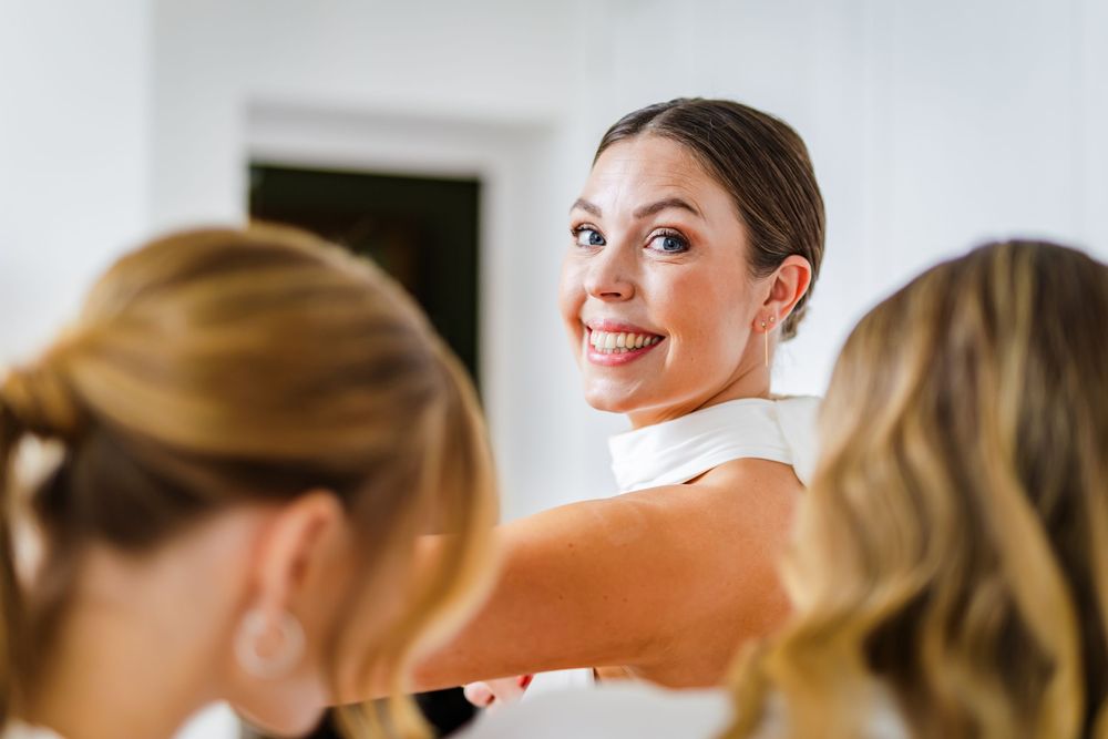 A group of people share laughter and smiles while getting ready in a bright indoor setting.