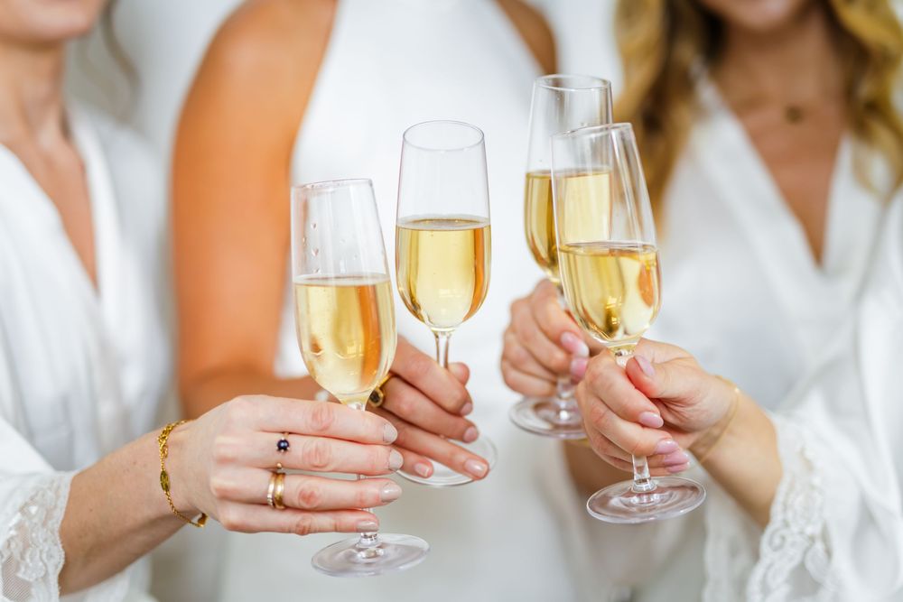 Several hands hold champagne flutes filled with golden bubbly wine in a celebratory toast.