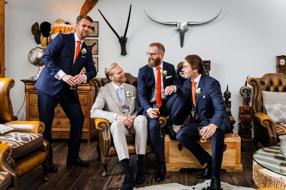 Group of people sitting and conversing on wooden benches in a rustic indoor setting.