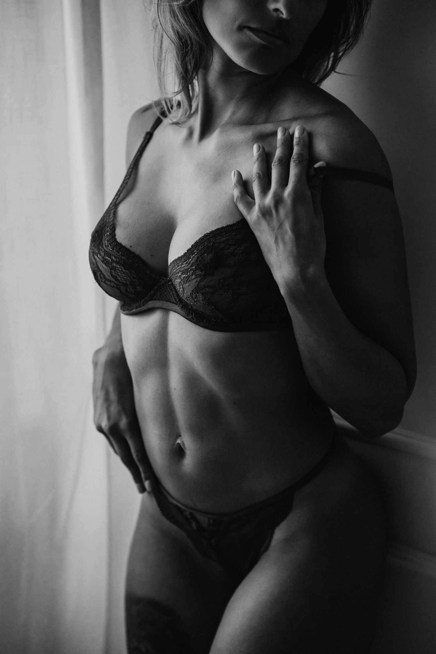 Artistic black and white boudoir photography with soft window lighting.