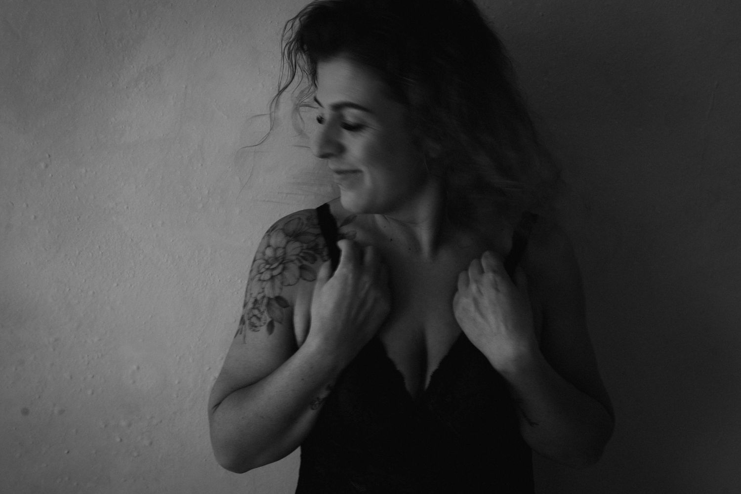 Artistic black and white boudoir portrait with dramatic shadows and intimate lighting.