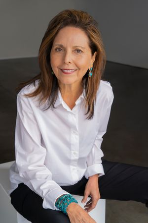 Professional portrait of person in white button-down shirt with turquoise jewelry.