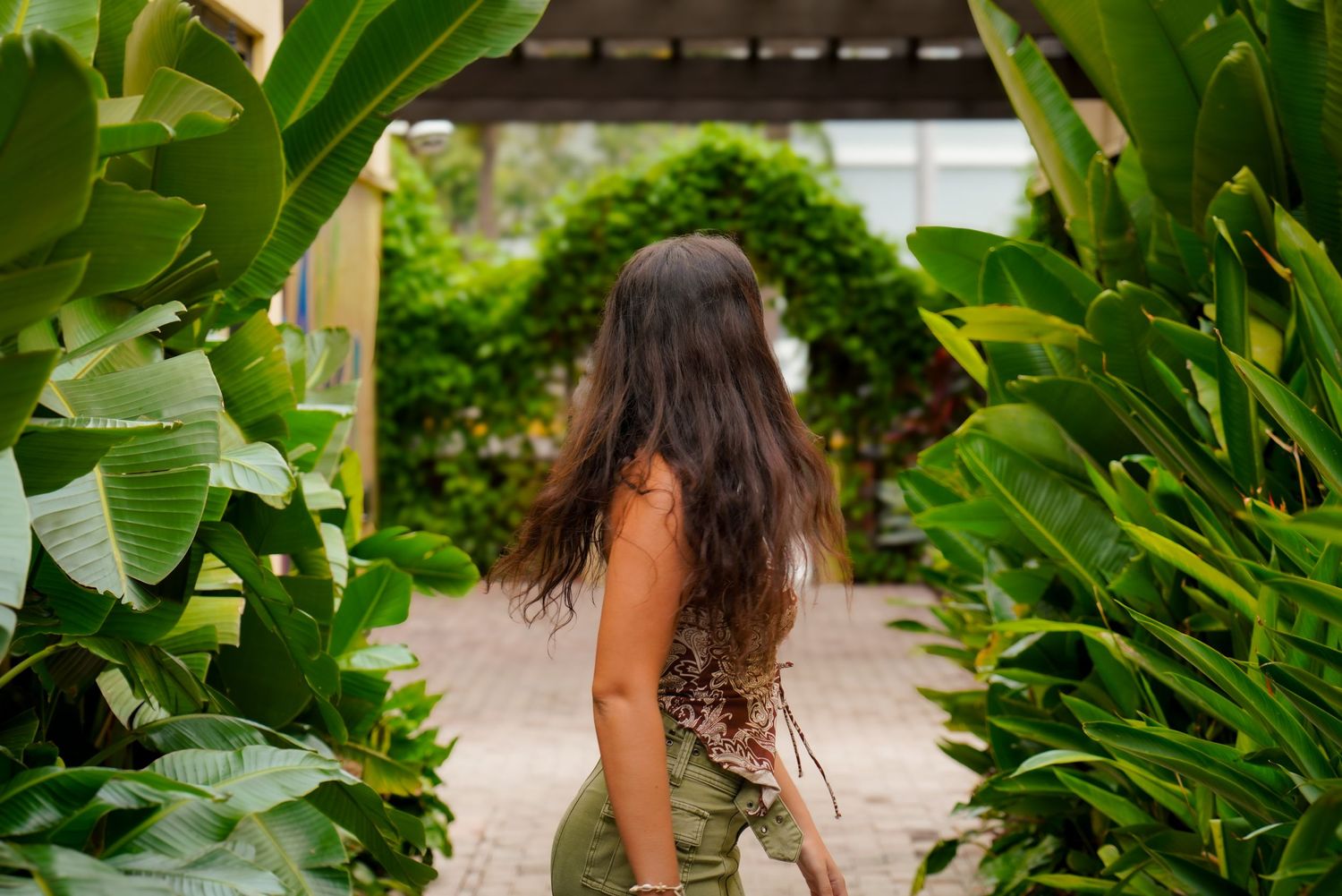 Lush tropical garden path framed by large green banana leaves.