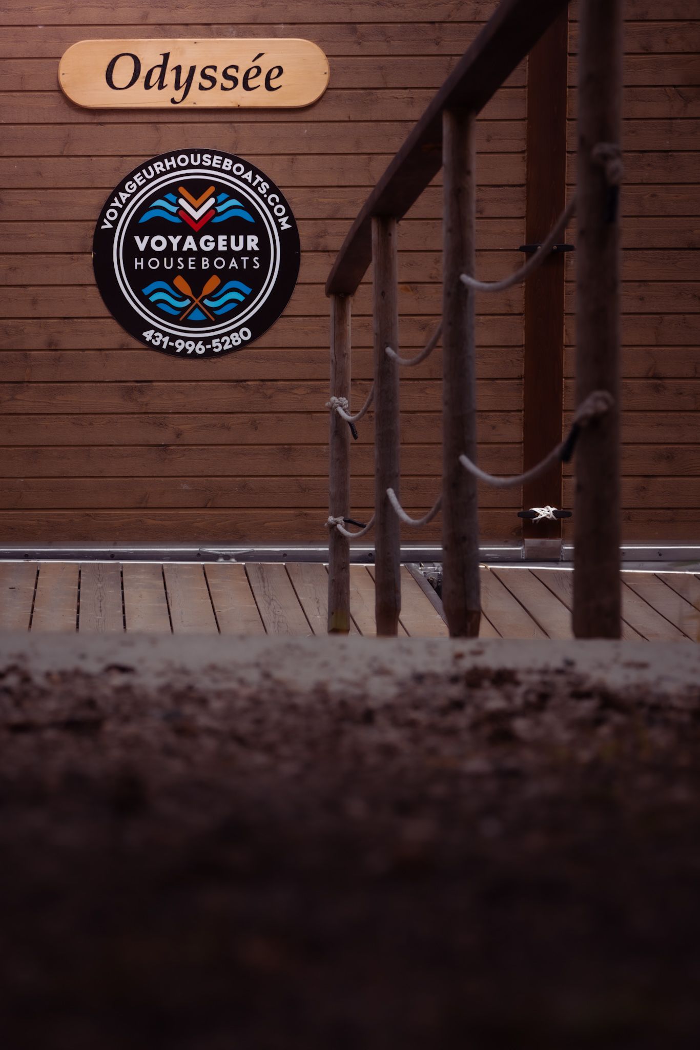 Odyssee and Voyageur Houseboats logo signs mounted on brown wooden wall.