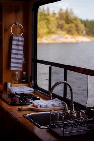Interior view of houseboat kitchen with sink and window overlooking serene lake landscape.