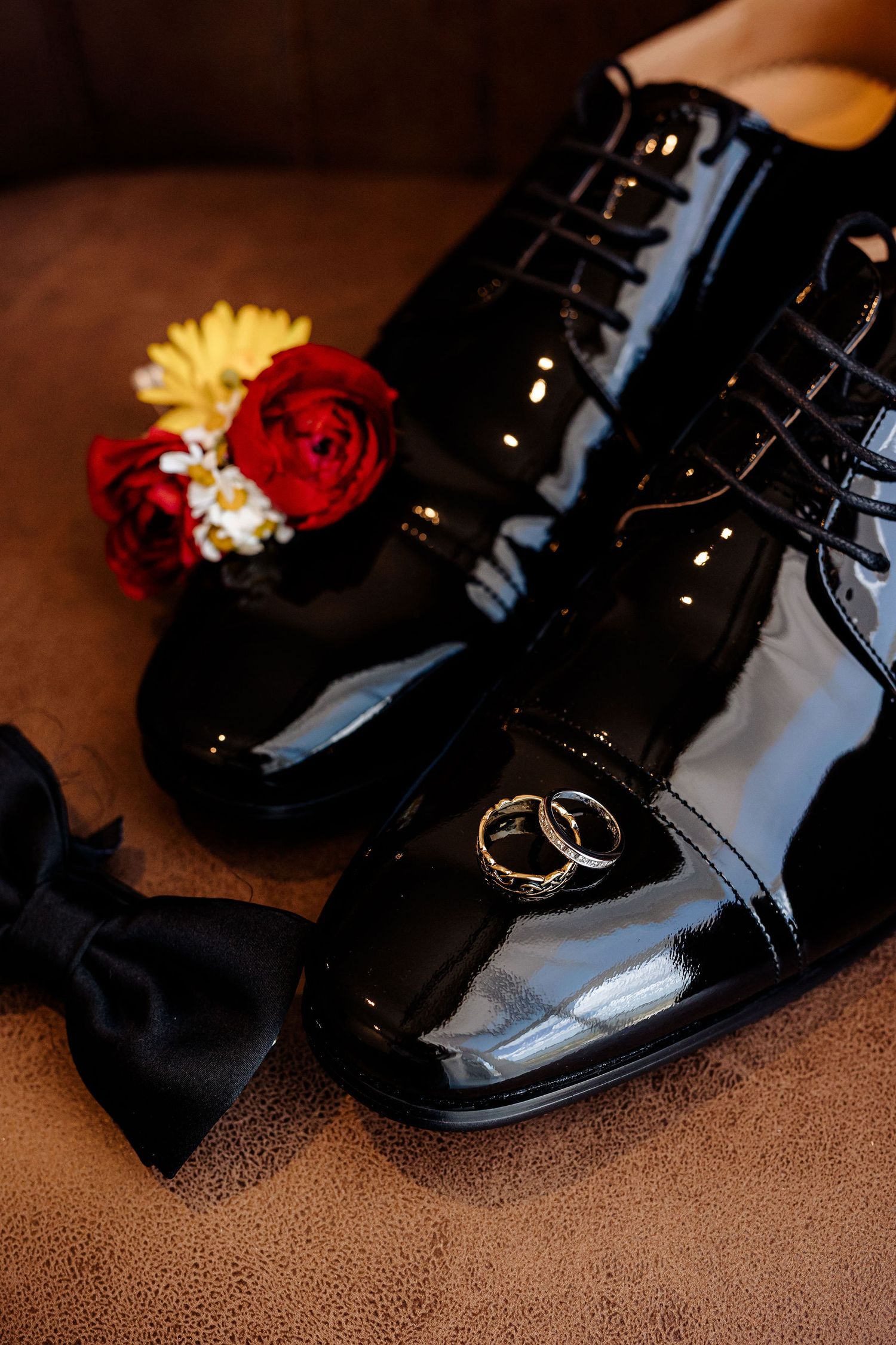 A sequence of close-up shots showing a glossy black formal dress shoe decorated with small red and yellow flowers.