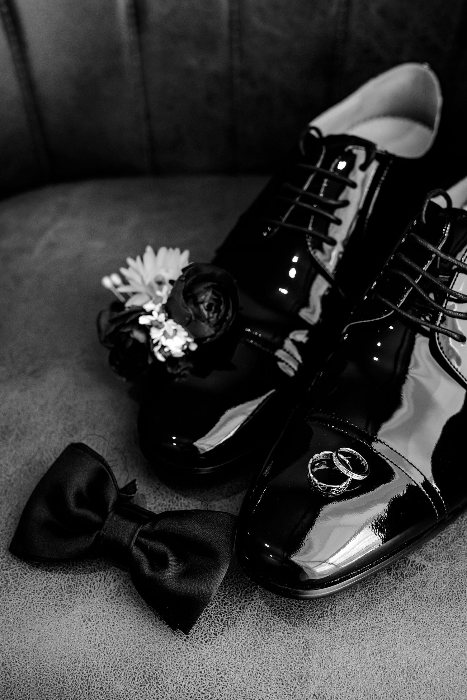 A close-up view of shiny black formal shoes with bows arranged in sequence with dark reflective leather surfaces.