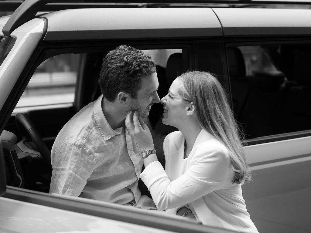 An intimate black and white moment captured through a car window.