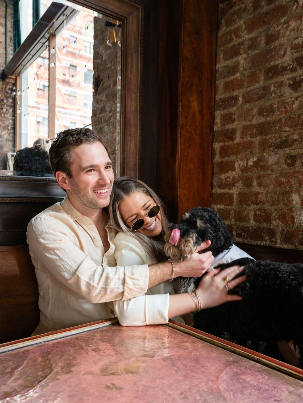 Candid moment of laughter with a black dog in a rustic brick interior.