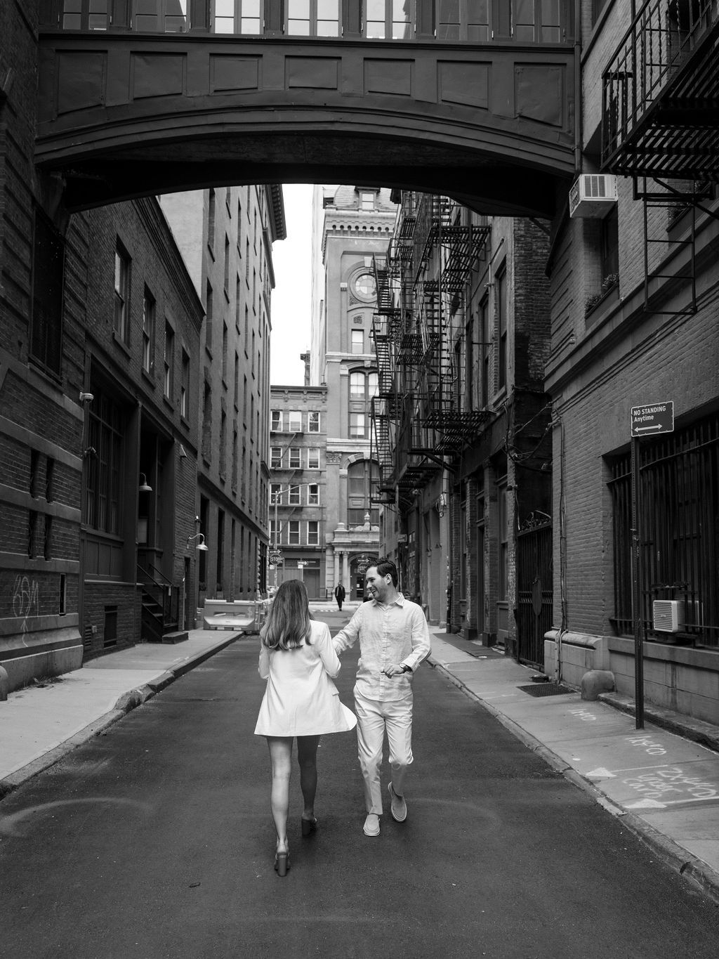 Black and white urban street scene with couple walking through historic neighborhood.