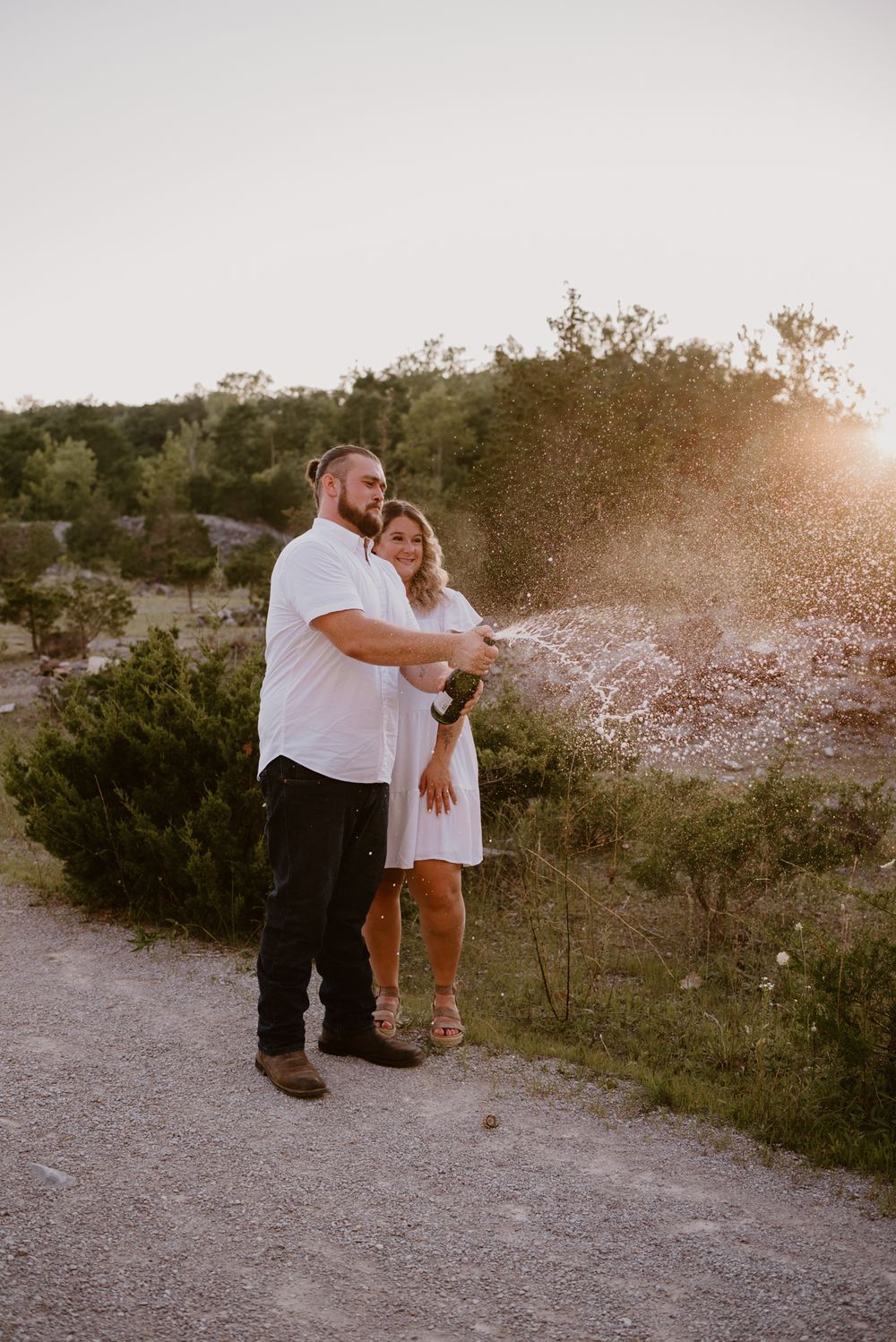 A couple shares playful moments on a rocky path at sunset.