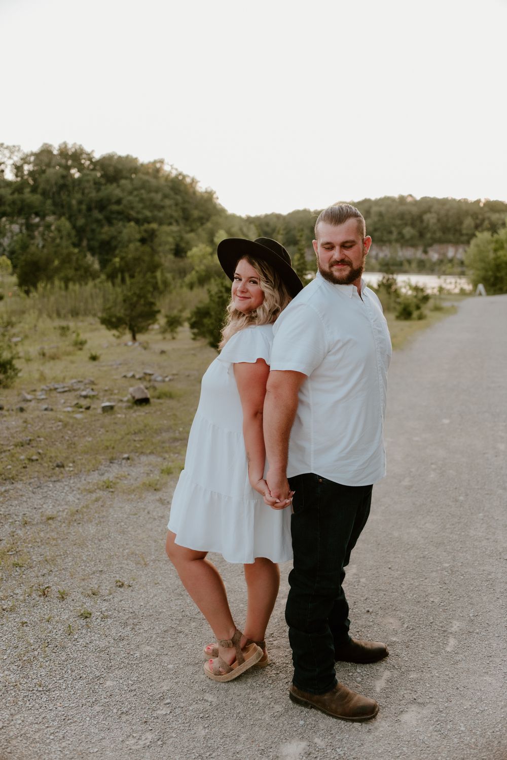 A couple shares an intimate moment while standing on a rocky path at sunset.