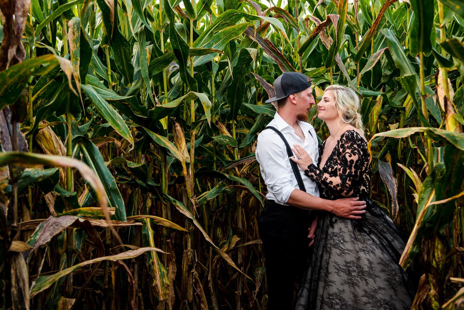 Romantic couple poses in a lush green cornfield during a photo session.