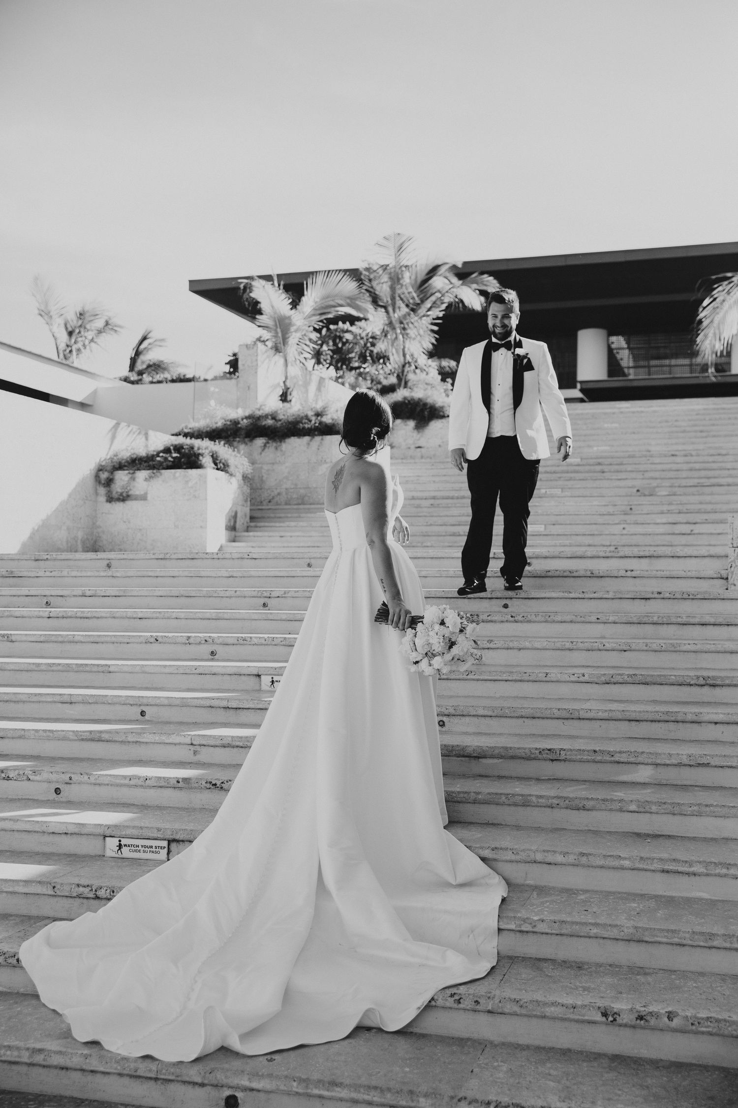 A wedding couple poses on outdoor stairs in black and white photography.