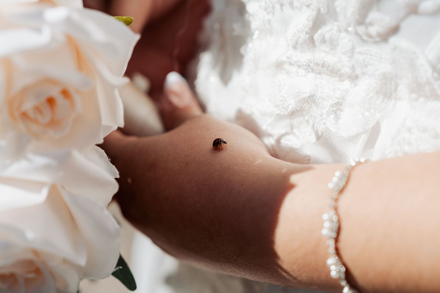 Delicate pearl bracelet and wedding dress details in soft lighting.