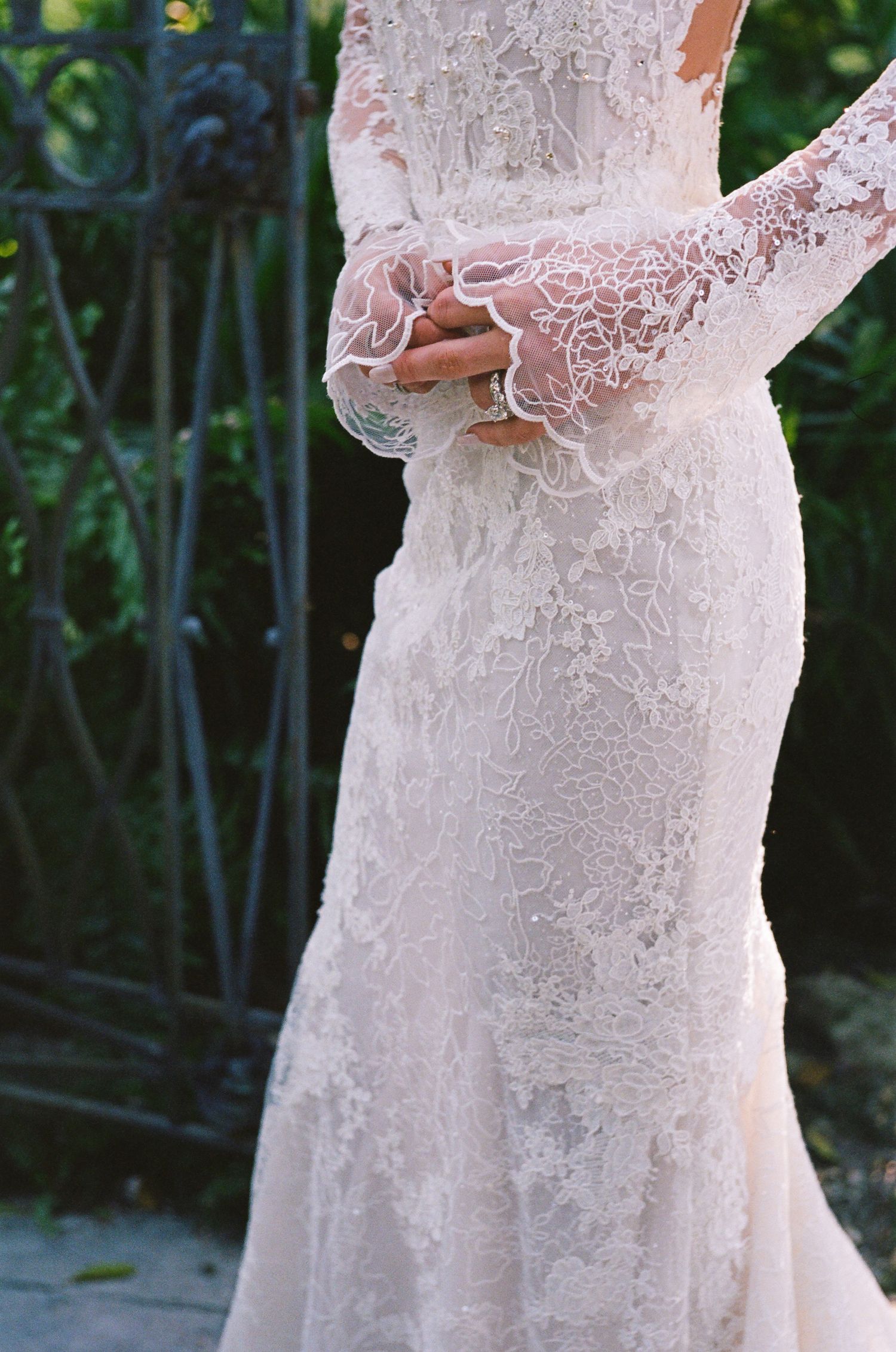 Close-up view of a blush pink lace wedding dress with delicate embroidered details and fitted silhouette.