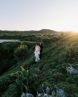 Figure in flowing white dress walks along scenic mountain ridge at golden hour while sun casts dramatic shadows.
