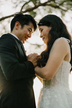 A romantic wedding couple shares an intimate moment together outdoors in soft natural lighting.